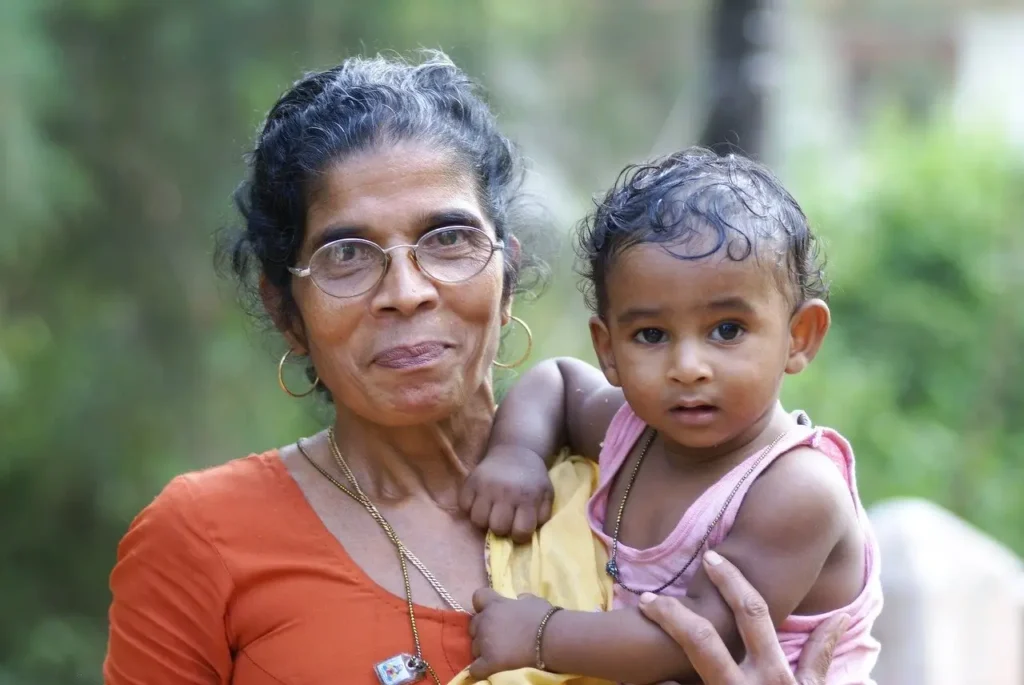 Grandmother holding her young grandchild outdoors.