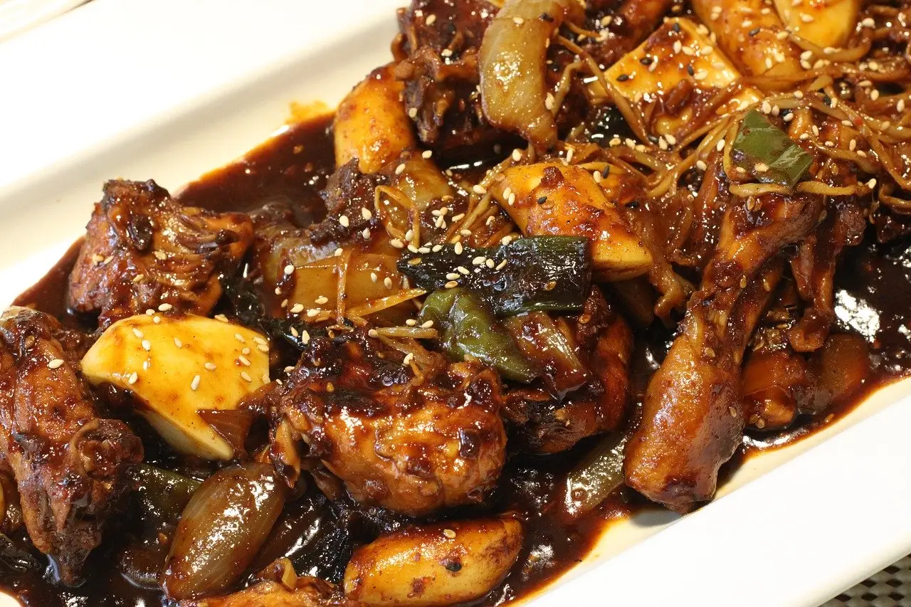 Close-up of spicy stir-fried chicken with vegetables in dark sauce.